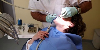 牙医在治疗一个女病人，手持枪伤