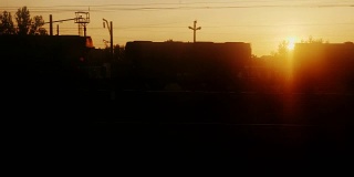 黎明时从火车窗口看到的景象。有树木、车站建筑和马车的剪影