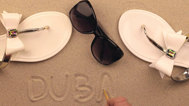 迪拜，在沙滩配件中间，手写的题字。符号和符号娱乐。
