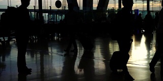 在机场，人群的剪影与晨光玻璃建筑形成对比