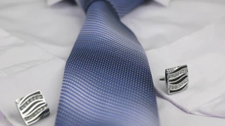蓝色领带和袖扣躺在白色衬衫上的视频。多莉。特写镜头。视频素材模板下载