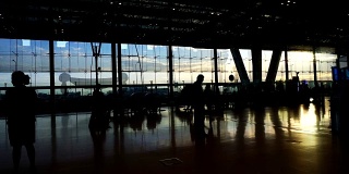 在机场，人群的剪影与晨光玻璃建筑形成对比