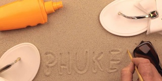 普吉岛的沙滩上手写碑文，沙滩配件之间。符号和符号娱乐。