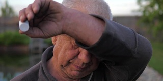 一位老人的肖像，用额头上的汗水擦拭他的手。