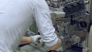 工人正在为汽车发动机安装螺栓，现代汽车生产车间视频素材模板下载
