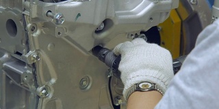 拧紧汽车发动机上的螺栓，由工人用手套、专用工具手动紧固