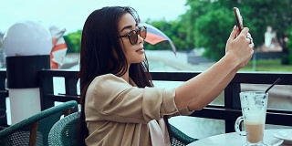 可爱又漂亮的亚洲女人拿着咖啡和手机