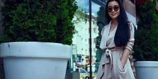 可爱和华丽的亚洲女人在时尚外套在街上