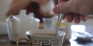 女性用手搅拌糖或牛奶在一杯热咖啡或茶中。慢动作