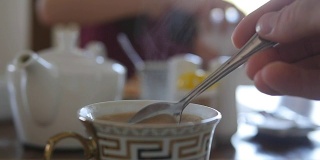 女性用手搅拌糖或牛奶在一杯热咖啡或茶中。慢动作