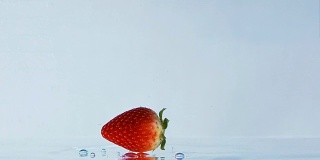草莓落下和在水上滚动的慢镜头。