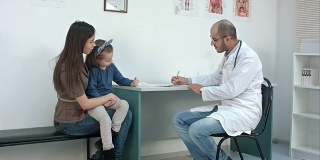 儿科医生填写医疗表格，而母亲与小女儿描述他们的问题