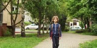 一个10-11岁的男孩放学回家。在他身后，他背着一个背包，手里拿着一个红色文件夹。他脸上的表情严肃而专注
