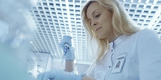 医学研究科学家使用微管填充试管的低角度拍摄。她在一家明亮的现代实验室工作。