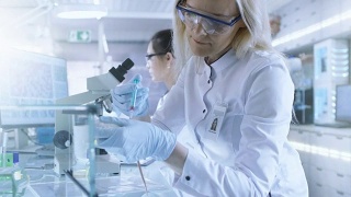 医学研究科学家在实验室用注射器注射的小鼠上测试疫苗实验药物。她在一家明亮的现代实验室工作。视频素材模板下载