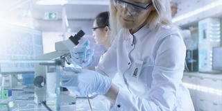 医学研究科学家在实验室用注射器注射的小鼠上测试疫苗实验药物。她在一家明亮的现代实验室工作。