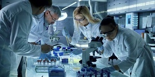 医学研究科学家团队共同致力于新一代实验性药物治疗。实验室看起来繁忙，明亮和现代。