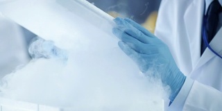 一个医学研究科学家打开冰箱盒子拿出有样品的培养皿并检查它的特写。他在一个繁忙的现代化实验室中心工作。