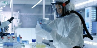 医学病毒学研究科学家工作在防护服与面具，她使用微型吸管。她在一个无菌的高科技实验室工作，研究设施。