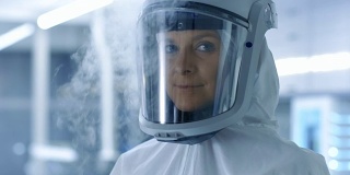 医学病毒学研究科学家穿着防护服，带着面具在寒冷的环境中微笑。她在一个无菌的高科技实验室/研究机构工作。