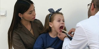 小女孩正在接受男医生的喉部检查