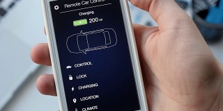 一名男子检查他的电动汽车的充电水平。电池充电。汽车遥控使用智能手机应用程序虚拟界面。