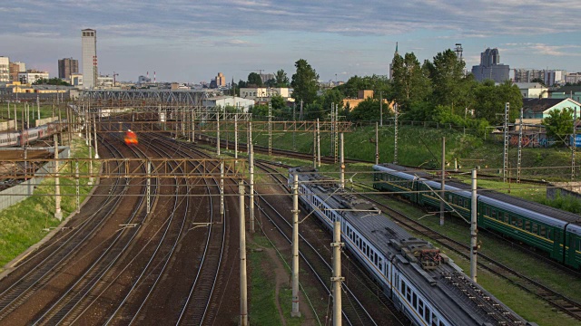 城市景观与许多铁路轨道在前景和移动的通勤客运列车