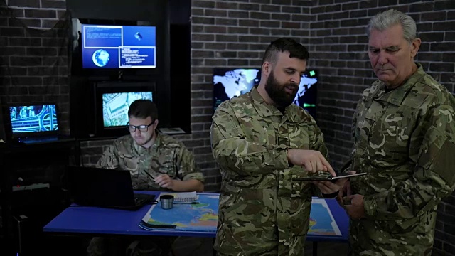 军事人员、指挥官和士兵，在军事总部，查看数字平板电脑