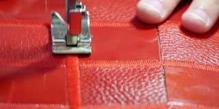 工厂生产的概念真皮制品。在缝纫机上缝合红色皮革