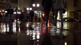 雨夜，在路灯的照耀下，雨点落在五颜六色的沥青上。不认识的人在雨伞下走，过有红绿灯的马路。美丽的彩色的散景。天气、交通、城市街道、现代城市生活方式的概念视频素材模板下载