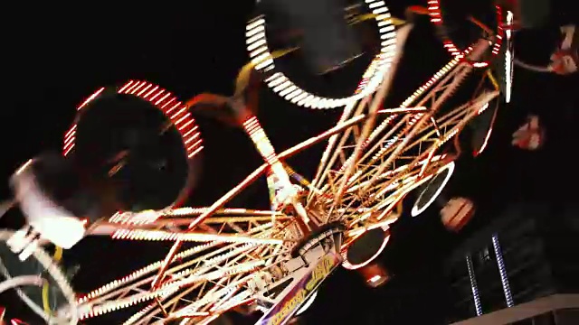 游乐园芭蕾舞者骑在五颜六色的灯光在晚上拍摄-有趣的活动视频背景