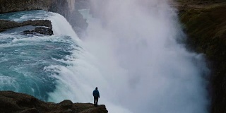 时间流逝的景观，在冰岛的海湾瀑布和人站在悬崖边，欣赏的观点