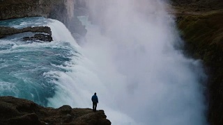 时间流逝的景观，在冰岛的海湾瀑布和人站在悬崖边，欣赏的观点视频素材模板下载