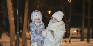 在冬天的公园里，年轻的妈妈牵着女儿的手和她亲吻