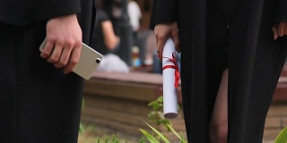 毕业生拿着智能手机和毕业证，等待毕业典礼