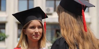 戴着学位帽的金发女人在听最好的朋友的毕业典礼
