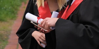 毕业那天，用智能手机浏览社交网络的毕业生朋友们