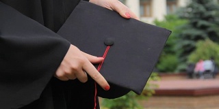 毕业日，女学生身着长袍，手拿带流苏的学位帽