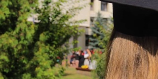 女戴着毕业帽看着快乐的学生把帽子抛向空中