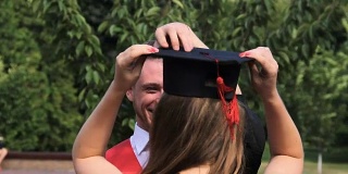 快乐的男学生拥抱姐姐，把他的毕业帽戴在她的头上