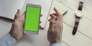 近距离的商人的手使用绿色屏幕的手机上网和电子邮件。