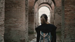 女游客正走在意大利罗马的历史中心。女人走过红砖砌成的古老拱门视频素材模板下载