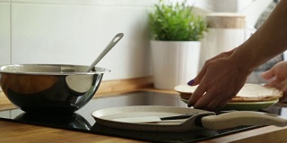 用手把准备好的煎饼从锅里移到盘子里。花板。