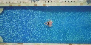 空中俯瞰特写:一个不认识的女人喜欢在游泳池里游泳