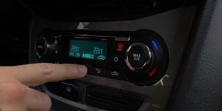 调节汽车空调按钮的手的特写。人使用汽车空调系统