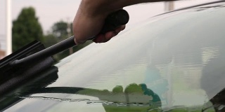 一名男子在加油站用橡皮擦擦挡风玻璃