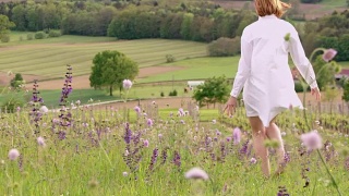 一个女人在春天的花丛中漫步，随风摇曳视频素材模板下载