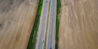 无人机拍摄的空高速公路。汽车行驶在乡间的道路上，穿过田野