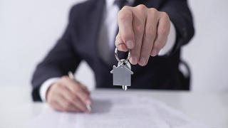 男子拿着房子或公寓的钥匙给买家，签署抵押贷款协议视频素材模板下载