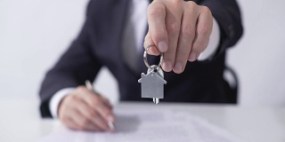 男子拿着房子或公寓的钥匙给买家，签署抵押贷款协议